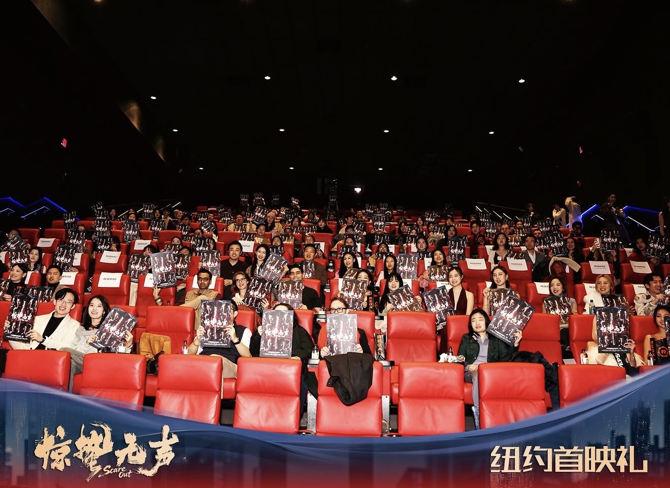 Audience holding film posters in red cinema seats at a New York premiere, with the premiere banner across the foreground.