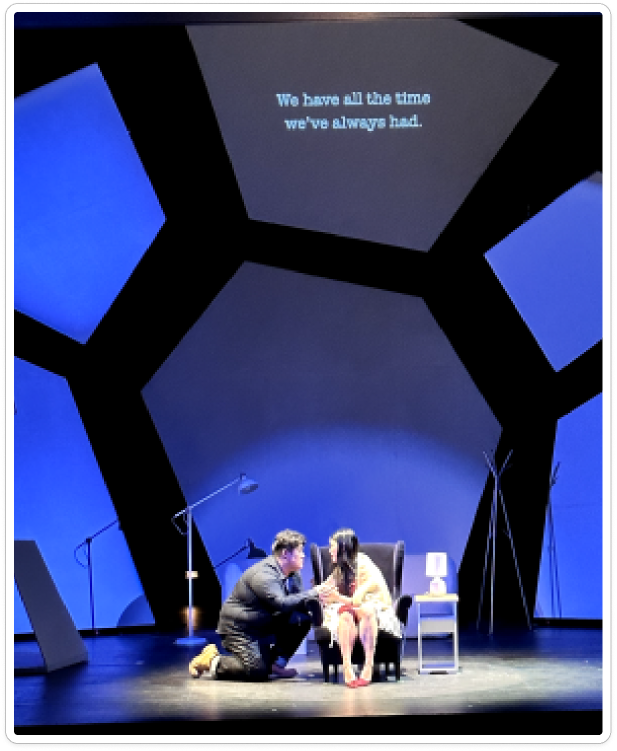 Actors within an illuminated angular stage set.